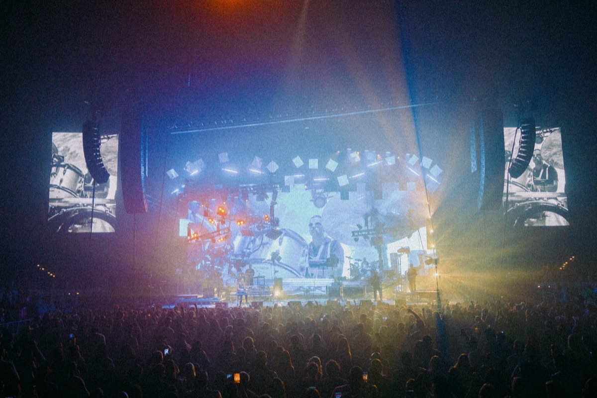 LANY on a wide arena stage in haze with the band on the video screens