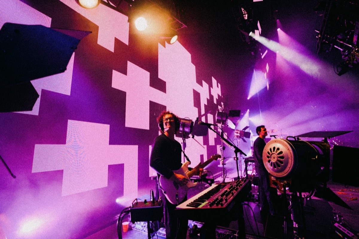 LANY on stage with purple pixel-pattern content across the LED wall