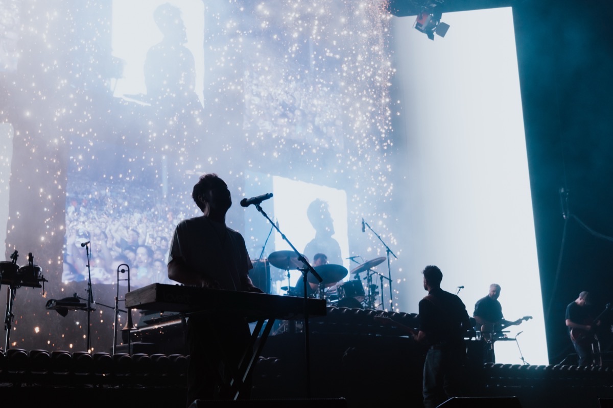 Mumford and Sons silhouetted against sparkling video content on the stage screens