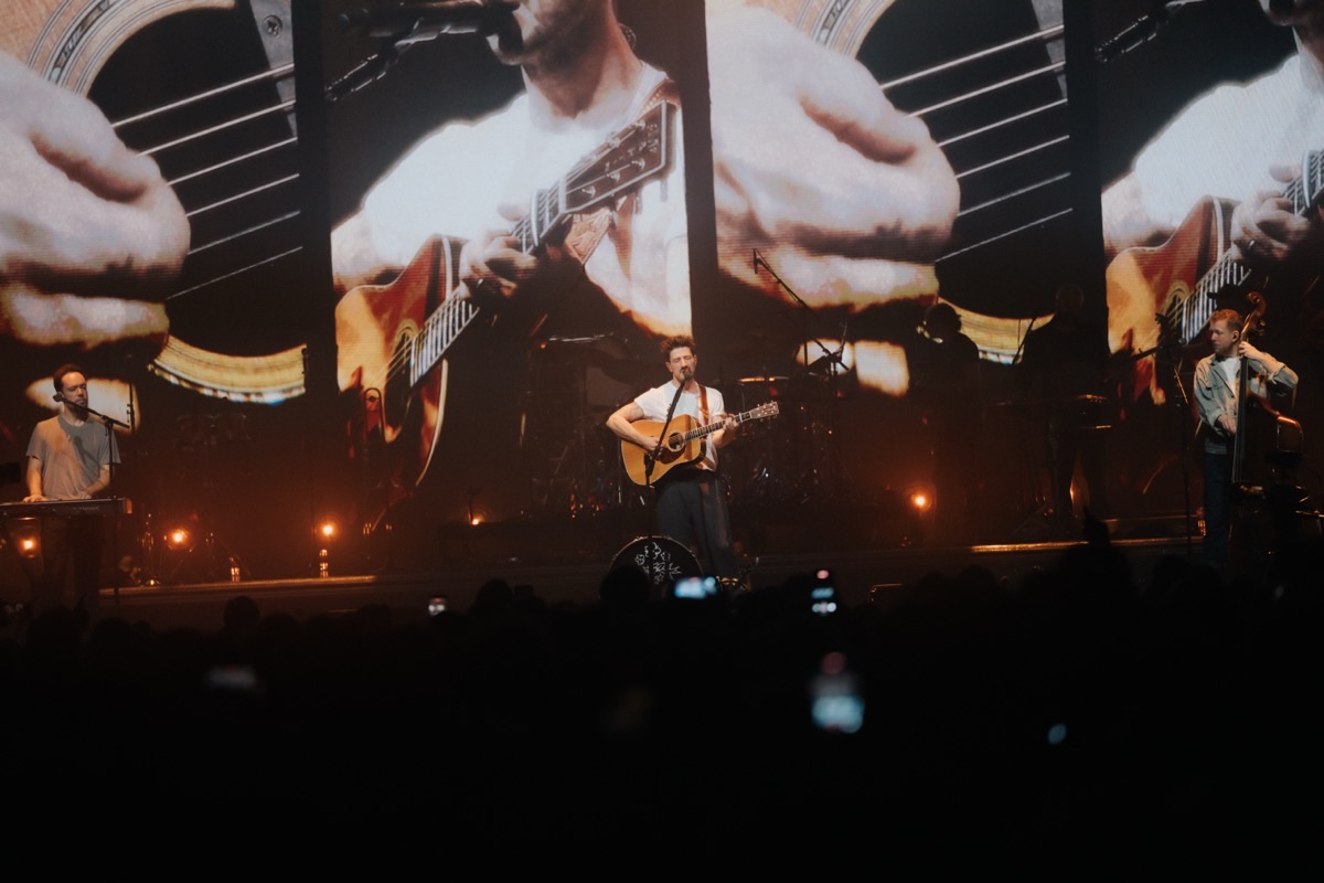 Mumford and Sons in London with an acoustic guitar close-up filling the main screen